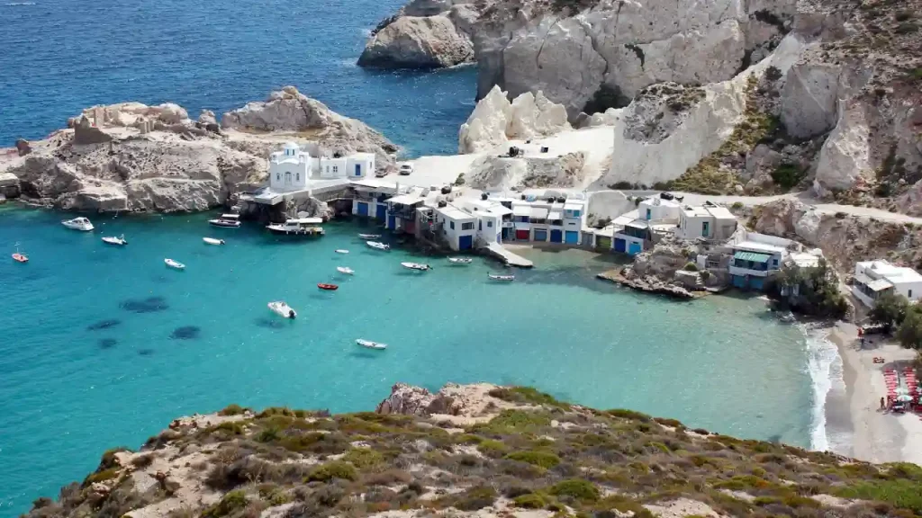 A secluded cove in Greece. A small harbor with colorful fishing boats bobbing in the clear blue water.
