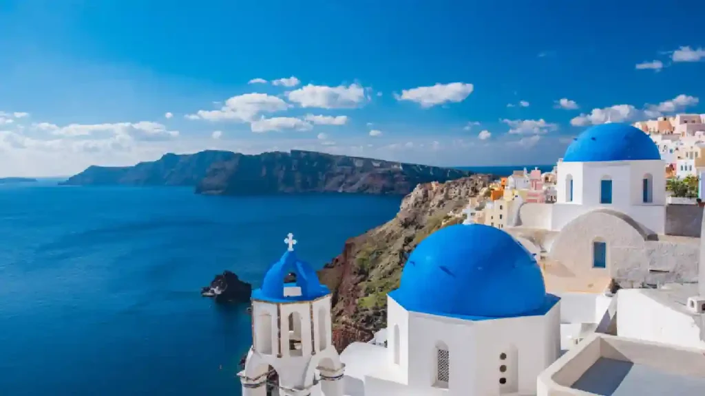 Whitewashed houses cascading down the cliffs of Oia, Santorini, with the Aegean Sea sparkling in the background