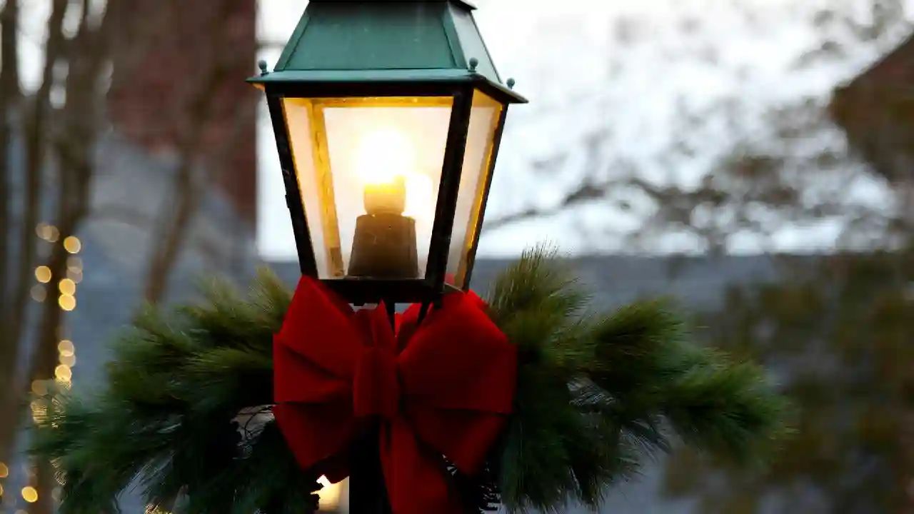 A lamp post decorated for Christmas with a red bow and pine needles