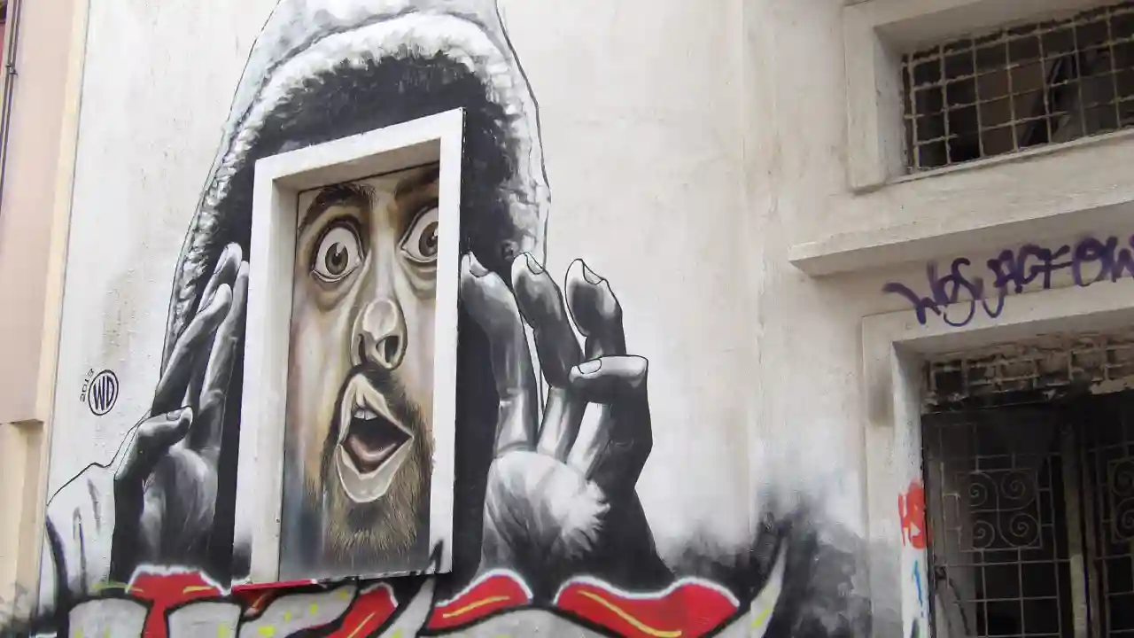 A street art mural depicting a man gazing out from a window. The mural is located in Exarchia, Athens, Greece, a neighborhood known for its street art scene.