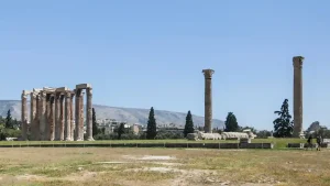 The Temple of Olympian Zeus in Athens, Greece. The temple is in ruins, with several standing columns and fallen stones.