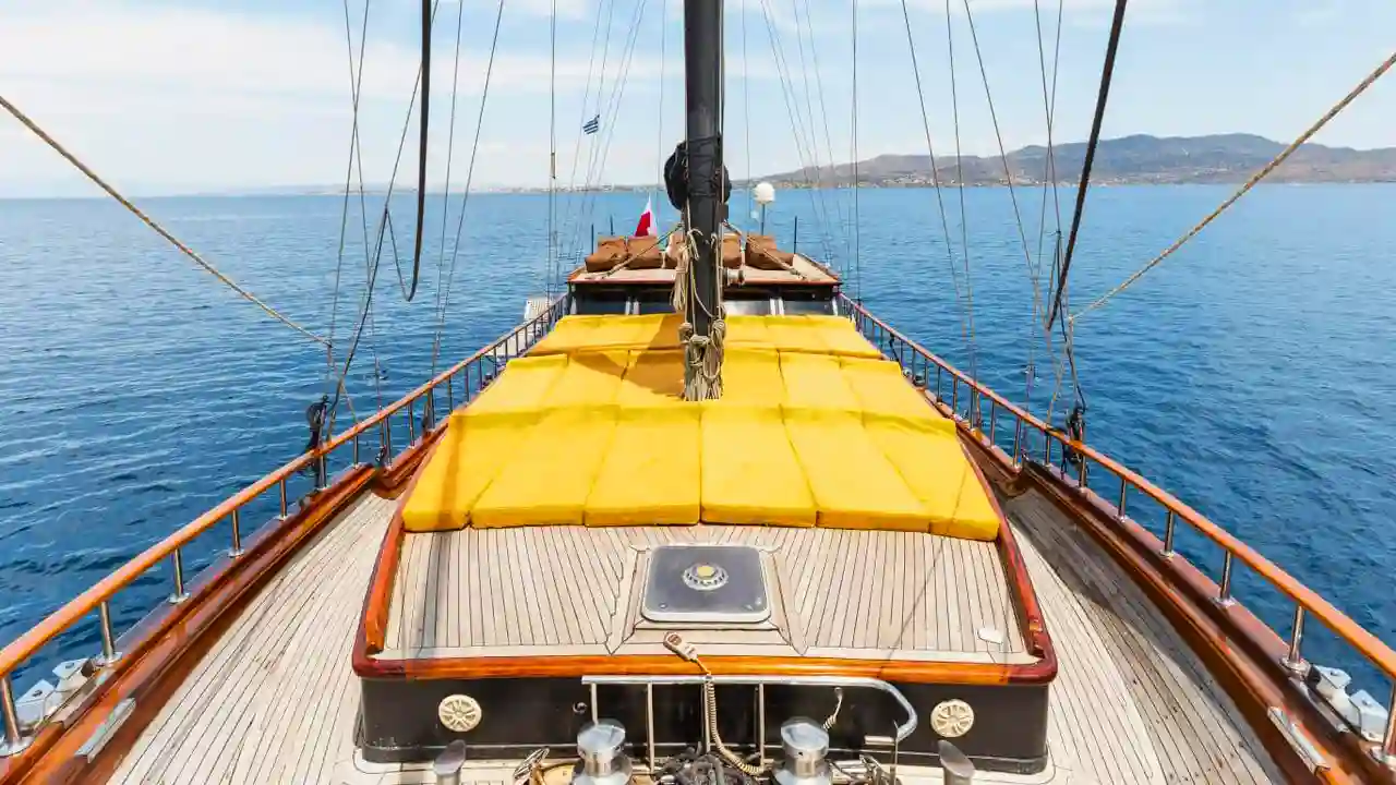 A spacious sun deck on a traditional Greek gulet with yellow cushions, offering panoramic views of the Aegean Sea. The deck is perfect for relaxing, sunbathing, and enjoying the sea breeze.