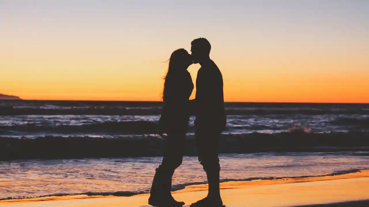 A couple enjoying a romantic date in Greece against a sunset-lit Greek island backdrop