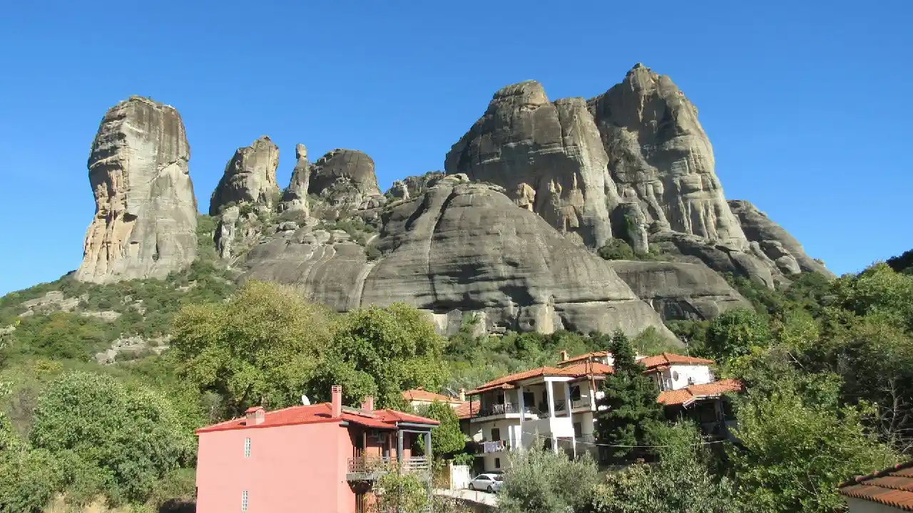 A breathtaking view of the Meteora Mountains in Greece. These dramatic rock formations rise majestically from the valley floor, creating a stunning natural landscape.