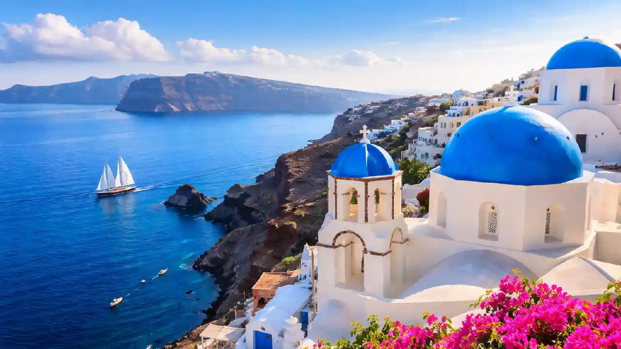 Scenic view of Santorini, Greece with white-washed buildings and blue domes overlooking the Aegean Sea, perfect for travelers checking Greek holidays today
