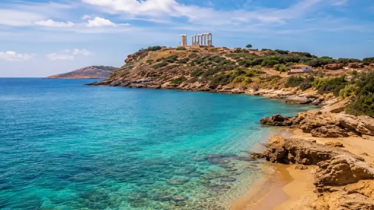 Turquoise water and rocky beach at Cape Sounio with the Temple of Poseidon overlooking the coast near Athens, Greece.